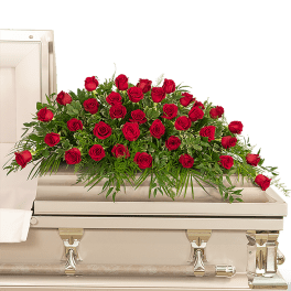 Red roses arranged on a white casket
