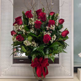 Red rose arrangement in a glass vase with a red ribbon