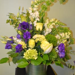 Purple and yellow floral arrangement in a glass vase