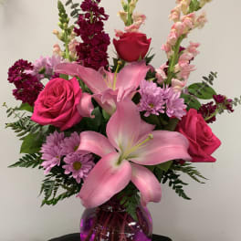 Pink lilies and roses in a purple glass vase