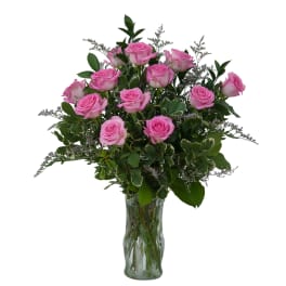 Pink roses arranged in a clear glass vase with greenery