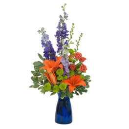 Orange lilies and purple flowers in a blue vase