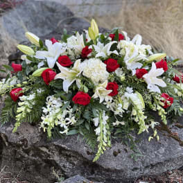 Casket spray of red roses and white lilies with trailing white flowers