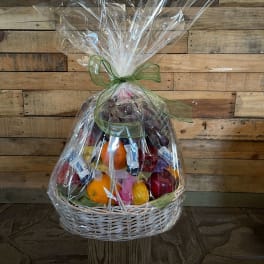 Wrapped fruit basket with oranges, apples, grapes, and candy bars