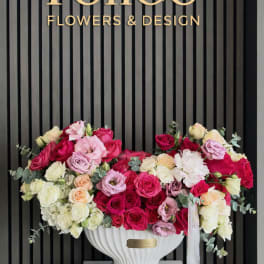 Large rose arrangement in a white pedestal vase