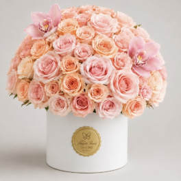 Pink and peach roses arranged in a white hat box with two pink orchids