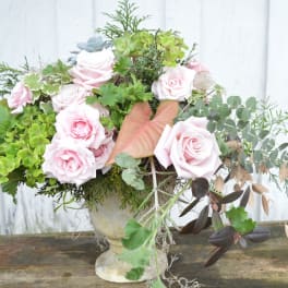 Pink roses and mixed greenery arranged in a stone vase