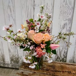 Peach roses and pink blossoms in a glass vase