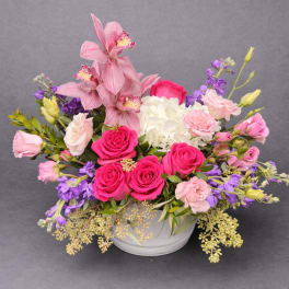 Pink and purple floral arrangement in a white bowl