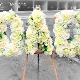 Large floral letters spelling "KAI" covered in white and cream roses