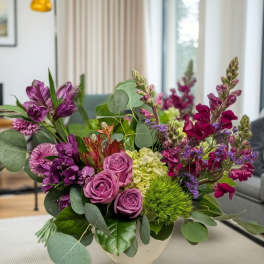 Purple and pink floral arrangement in a white vase