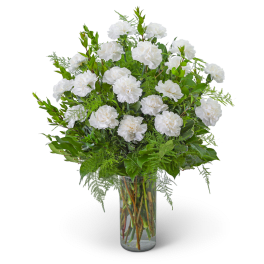White carnations in a clear glass vase with green foliage