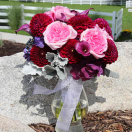 Pink and burgundy bouquet in a glass vase with a ribbon