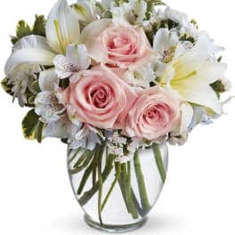 Pink roses and white lilies arranged in a clear glass vase
