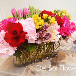 Mixed bouquet of roses, hydrangeas, and tulips in a glass vase