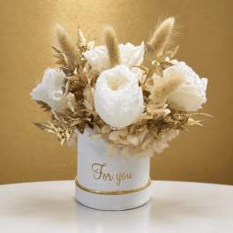 White floral arrangement in a white container with gold accents