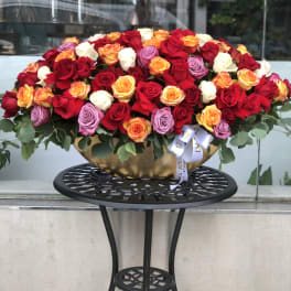 Large mixed rose arrangement in a gold bowl on a black stand