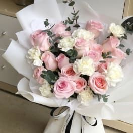 Bouquet of pink roses and white carnations wrapped in white paper