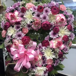 Heart-shaped floral wreath with pink and purple flowers and a pink ribbon bow