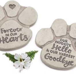 Two paw-print memorial stones with a small white flower accent