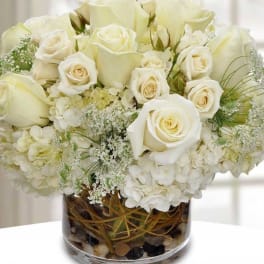 White roses and hydrangeas arranged in a glass vase.
