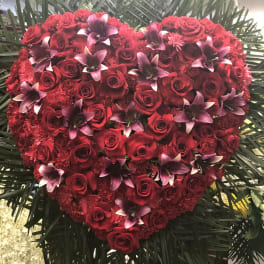 Heart-shaped arrangement of red roses and purple orchids