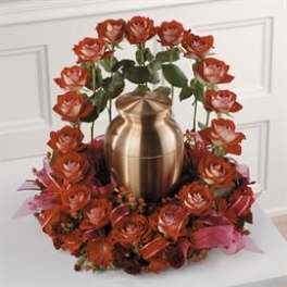 Red roses arranged around a gold urn centerpiece