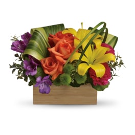 Low wooden box arrangement with orange roses, yellow lilies, and purple blooms.