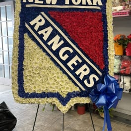 Large floral tribute sign reading NEW YORK RANGERS with blue and red flowers.