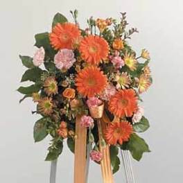 Orange and pink floral standing arrangement with ribbon streamers
