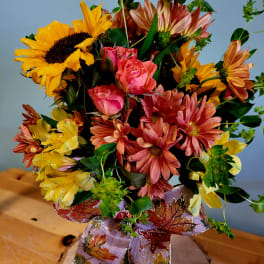 Bouquet of sunflowers, pink roses, and daisies with a decorative ribbon
