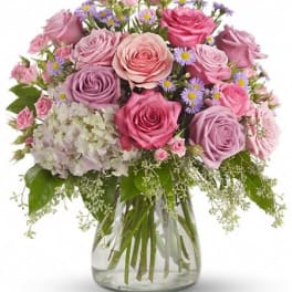 Bouquet of pink and lavender roses with white hydrangea in a glass vase