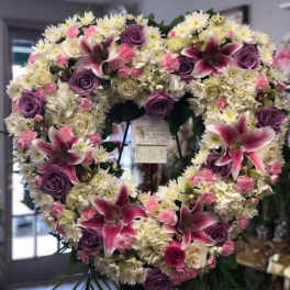 Heart-shaped floral wreath with pink lilies, purple roses, and white daisies