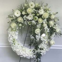 White roses and daisies arranged in a large heart-shaped wreath on a stand