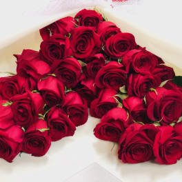 A bouquet of red roses wrapped in white paper