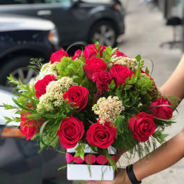 Bouquet of red roses and green filler in a white box