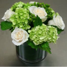 White roses and green hydrangeas in a dark glass vase