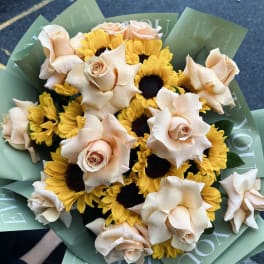 Bouquet of peach roses and yellow sunflowers wrapped in green paper