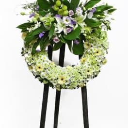 Standing floral wreath with white and green flowers on a black easel