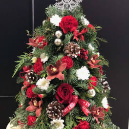 Christmas tree-shaped arrangement with red and white flowers and pinecones