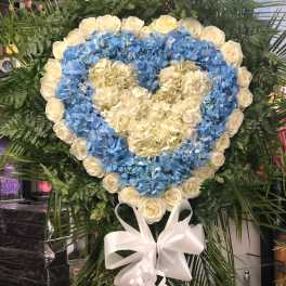 Heart-shaped floral wreath with blue hydrangeas and white roses, tied with a white bow