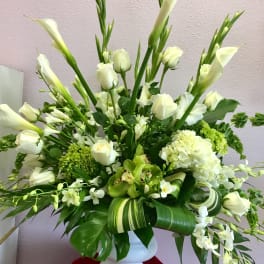 White floral arrangement in a white vase with tall calla lilies and roses