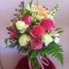 Bouquet of pink and peach roses with white flowers in a glass vase