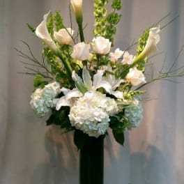 White calla lilies and hydrangeas in a tall glass vase