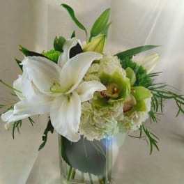 White lilies and green orchids in a clear glass vase