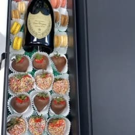 Gift box with champagne and chocolate-covered strawberries and macarons