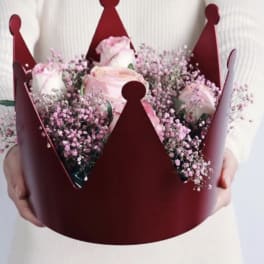 Pink roses in a burgundy crown-shaped bouquet holder