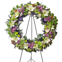 Floral wreath on a black easel with purple, white, and green blooms