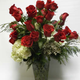 Red roses and white hydrangeas arranged in a clear glass vase