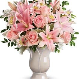 Pink lilies and roses arranged in a white vase
